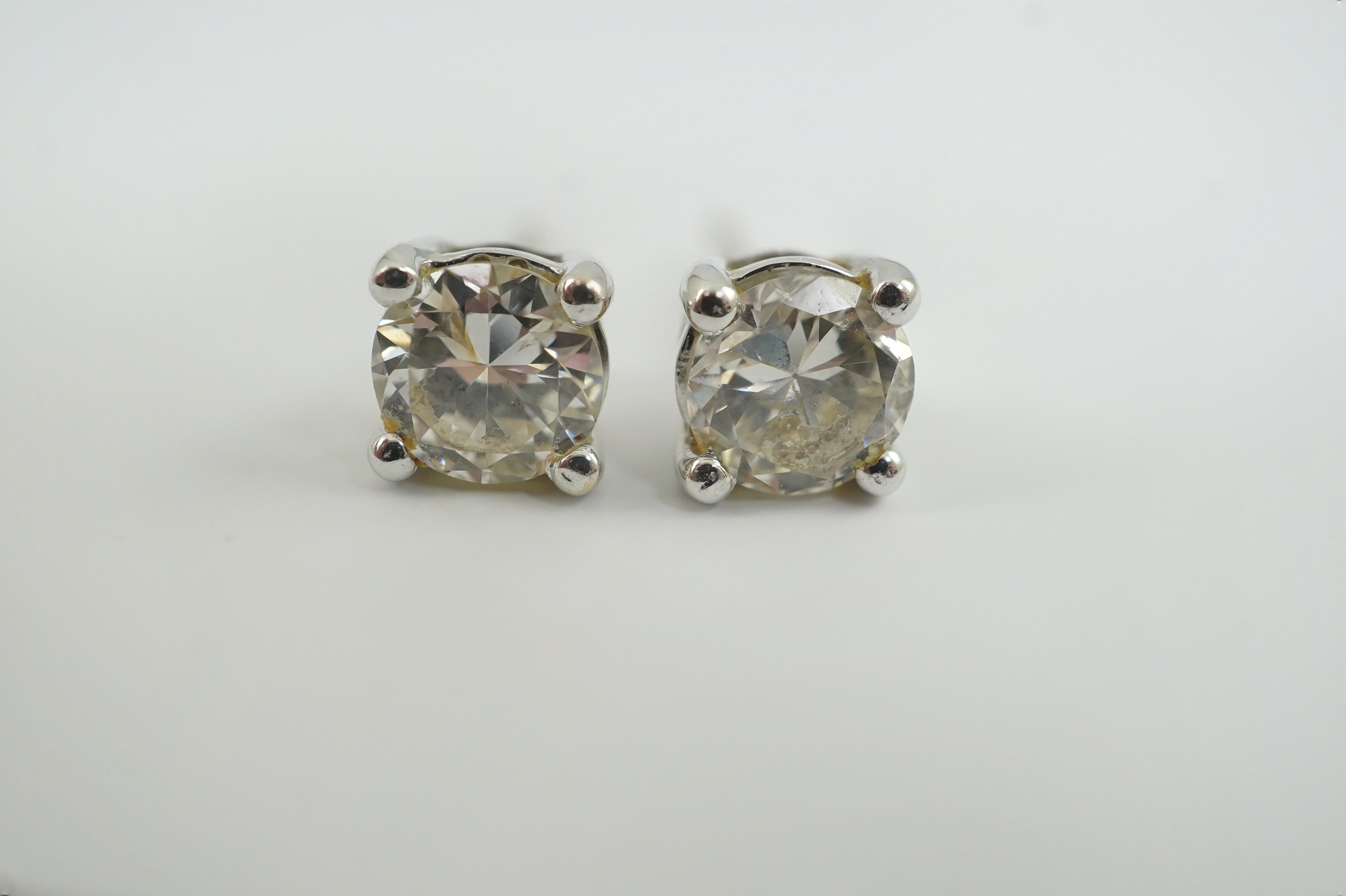 A modern pair of 18k white gold and solitaire diamond set ear studs